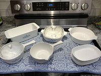 Full set of Corning Ware cookware with Cornflower Blue pattern and lids laid out on stove
