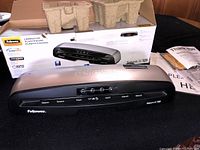 Photo of the Fellows Saturn 3i 125 laminator with its box and protective packaging inside the box.