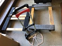 Photo showing the compact Magna Cart hand truck with wooden floor dollies in the background.