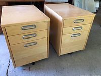 Pair of rolling office cabinets showing front drawer faces with metal handles and light wood finish.