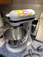 Front-right view of mixer with flame decals, wire whip in bowl
