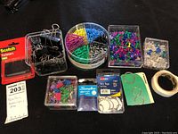 Wide shot of the lot showing multiple office supplies including push pins, binder clips, paper clips, key rings, tape, and fasteners.