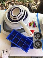 Full set of collapsible bowls, silicone ice cube trays, silicone measuring spoons, funnel, and collapsible strainer bins arranged on table