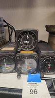Front view of four aviation cockpit instruments stacked side by side showing dials and markings, including ADF indicator and heading indicator.