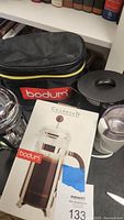 Photo showing Bodum Chambord French press coffee maker, travel electric coffee maker, and Bodum carrying bag