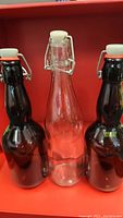 Three glass bottles with stopper caps, showing two brown glass and one clear bottle with loose transparent cap