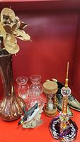 Overview of items including glass vases, wooden hourglass, brass shoes, bird figurine, and tall vase with flower