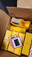 Open box containing yellow plastic slide storage trays and loose 2x2 mounted slides