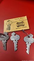 Three vintage American Tourister bellhop style keys with original yellow envelope featuring cartoon bellhop and branding.