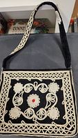 Front side of the vintage embroidered bag showing floral and swirl designs with central red bead