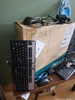 Photo showing four wired keyboards, a corded mouse, cords, and a cardboard box with Acer branding.