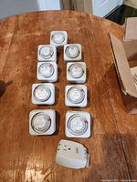 Nine white Intermatic indoor light timers arranged on a wooden table, with one additional small white plug-in timer.