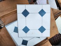 Top view of several stacked vinyl tiles showing white base with blue diamond pattern.