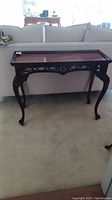 Full view of dark wood accent table showing overall shape and size beside sofa.