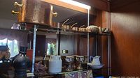 Wide shot of copper kitchenware and stoneware on glass shelf