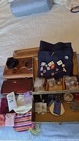 Photo of assorted pins on black fabric, decorative boxes behind, small pouches and cases in front