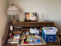 Wide view of wooden desk showing lamp, pen set, trays with office supplies, trinket box, and assorted papers and cards.