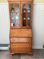 Full view of wood hutch with glass display doors on top and drawers below showing size and structure.