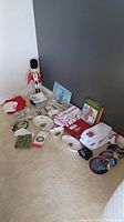 Full view of all Christmas items including dishes, linens, plates, nutcracker, and paper goods on carpeted floor against wall