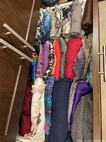 Drawer filled with various women's scarves, showing folded scarves in multiple colors and textures including patterned and solid colors.