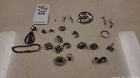 Photo showing assortment of sterling silver rings, bracelets, earrings, and pendants arranged on a flat surface.