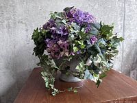 Full view of the faux flower arrangement on wooden surface against concrete wall background.