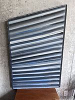 Front view of large abstract wooden board painting showing ribbed horizontal texture with shades of grey, black, and blue.