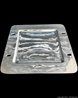 Square stainless steel serving platter shown against black background, highlighting its hammered texture and cut-out handles.