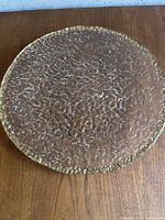 Top view of the large textured clear glass plate showing the intricate surface texture and gold edging.