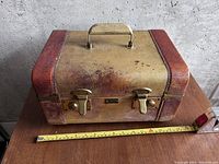 Closed view of vintage train carry case showing exterior condition with handle and metal clasps.
