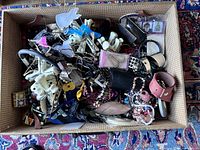 Top view of vintage suitcase filled with assorted costume jewelry showing bracelets, beads, and rings in a mixed disorganized pile.