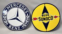 Both the Blue Sunoco and Mercedes Benz enamel signs shown side by side, displaying their full front designs.