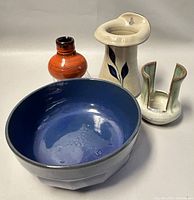 Four pottery pieces arranged with bowl in front and three vases behind.