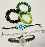All six beaded bracelets arranged for clear visibility; shows variety in style and color including the macrame and floral designs.