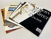 Photo showing front covers of seven jazz record albums fanned out, with 'Modern Jazz Quartet - For Ellington' album on top.