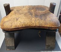 Top view of the saddle showing the worn leather seat with discolorations and stains.