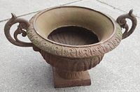 Side angle showing the ornate curved handles, fluted bowl, and pedestal base with patina.