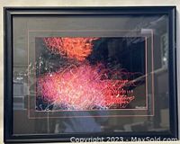 Framed print showing abstract light trails in orange, pink, and purple tones with black frame and double matting.