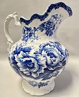 Side view of large semi-porcelain pitcher showing blue floral pattern and sculpted handle