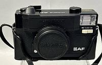 Front view of Minolta AF 35mm film camera with lens cap on and built-in flash on.