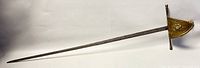 Full length view of vintage decorative wall sword with brass guard lying flat to show overall shape and length