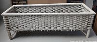 White wicker plant stand showing front and top perspective, rectangular woven body with legs
