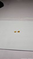 Two small pear cut golden yellow sapphires shown on white background, centered and well-lit to show color and shape.
