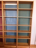 Front view of the two wooden book shelves side by side against a wall.