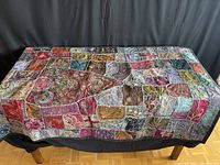 Full view of the patchwork quilt showing the multi-colored and heavily beaded fabric squares.