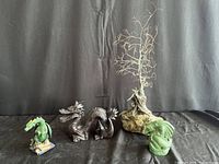 Wide shot showing three dragon figurines and the metal wire tree on a rock base.