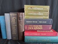 Photo of nine classic hardcover books by various authors stacked vertically and horizontally, titles visible on spines.