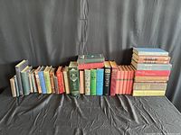 Full view of the lot of 38 old books of various sizes and colors on a black cloth backdrop