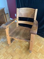 Front view of the antique solid wood rocking chair showing wider seat and carved floral motifs on the backrest.
