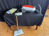 Kenmore canister vacuum with flexible hose and wand on black table.